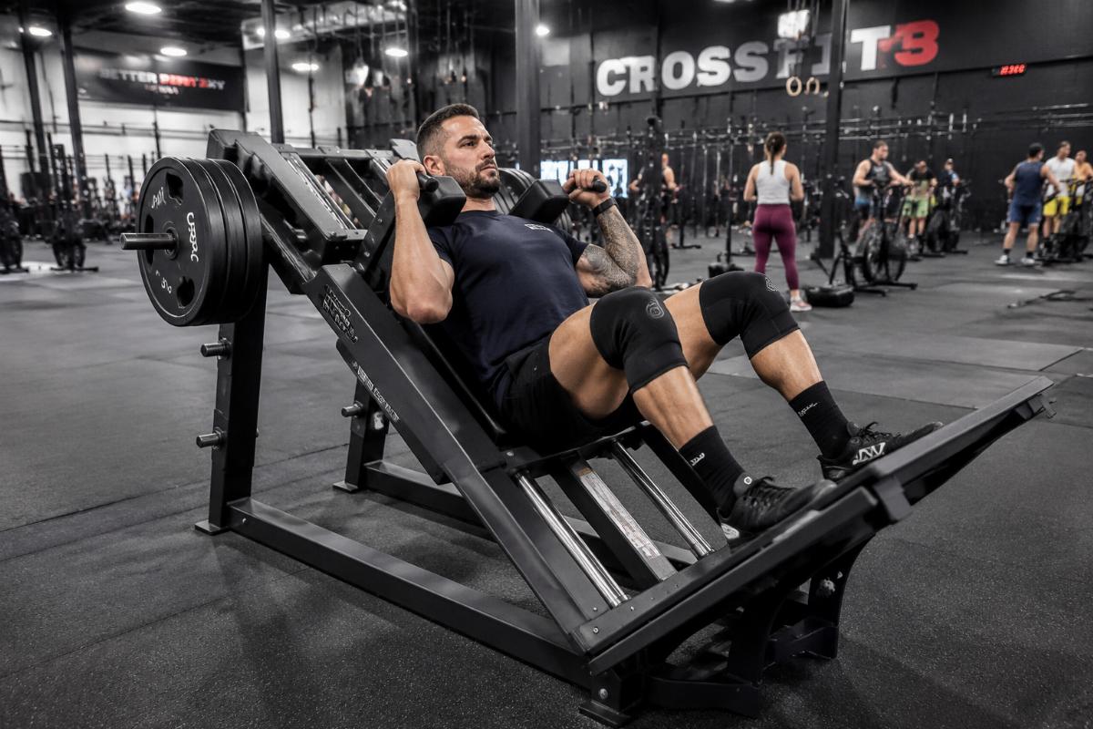 Linear bearing hack squat machine in active use at a high-volume CrossFit facility