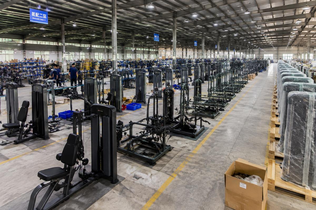 Factory floor showing rows of commercial strength machines in various stages of assembly and packaging